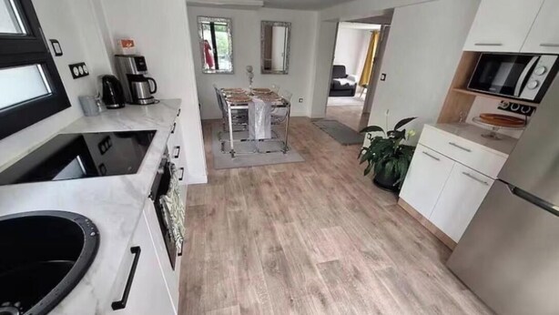 Una cocina moderna con comedor, piso de madera y armarios blancos.