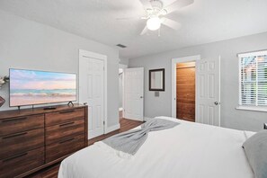 A bedroom with a bed, a dresser, a television, and a ceiling fan. - Heated Pool + Spa, Fenced Yard, Fire Pit, Sleeps 8, 15 Min to AMI (Bradenton)