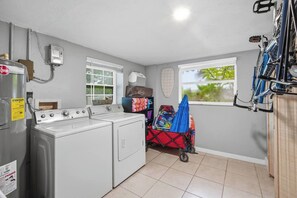 A laundry area with a washer and dryer, a window with blinds, and a bicycle rack. - Heated Pool + Spa, Fenced Yard, Fire Pit, Sleeps 8, 15 Min to AMI (Bradenton)