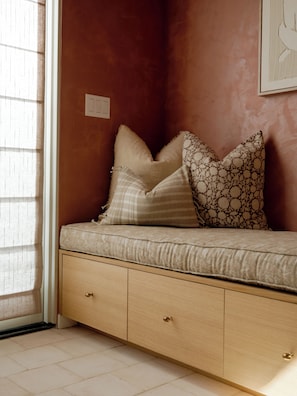 Ein Zimmer mit einem Bett, einem Fenster mit Jalousien und einem an der Wand montierten Lichtschalter.