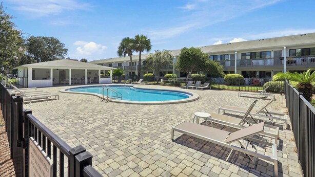 A pool area with lounge chairs and a covered seating area, surrounded by a building with balconies. - Suite Y'all | 2-Min Walk to Beach | Pet Friendly (Santa Rosa Beach)