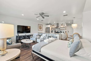 A hotel room with a bed, a desk, a TV, a kitchenette, and a ceiling fan. - Suite Y'all | 2-Min Walk to Beach | Pet Friendly (Santa Rosa Beach)