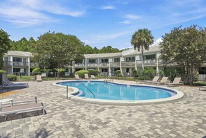A swimming pool with lounge chairs and a covered seating area, surrounded by a multi-story building with balconies. - Suite Y'all | 2-Min Walk to Beach | Pet Friendly (Santa Rosa Beach)