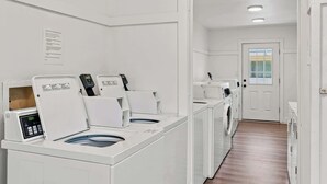 A laundry room with multiple washing machines and dryers, a wooden floor, and a white door with a window. - Suite Y'all | 2-Min Walk to Beach | Pet Friendly (Santa Rosa Beach)