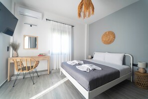Una camera d'hotel moderna con un letto, una scrivania, una sedia, una TV e una finestra con tende.