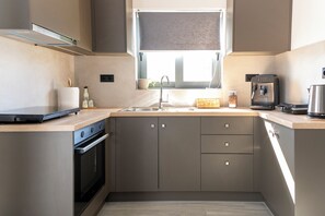 Una cucina moderna con forno integrato, macchina da caffè e finestra sopra il lavello.