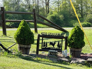 A wooden sign with a number and a silhouette of a deer and trees, surrounded by potted plants and a wooden fence. - Enjoy a private getaway - outdoor adventure at your doorstep! (Dansville)