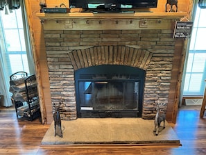 A fireplace with a stone surround, a mounted television above it, and two deer figurines on either side. - Enjoy a private getaway - outdoor adventure at your doorstep! (Dansville)