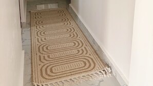 Ein Flur mit einem gemusterten Teppich, einem Spiegel und einer Tür zu einem weiteren Raum.