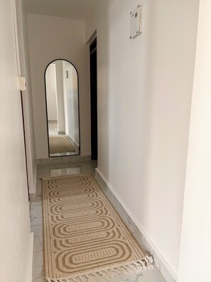 A hallway with a patterned rug, a mirror, and a door leading to another room. - Modern 1-Bedroom Coastal Apartment in Mtwapa Near the Beach. (Mtwapa)