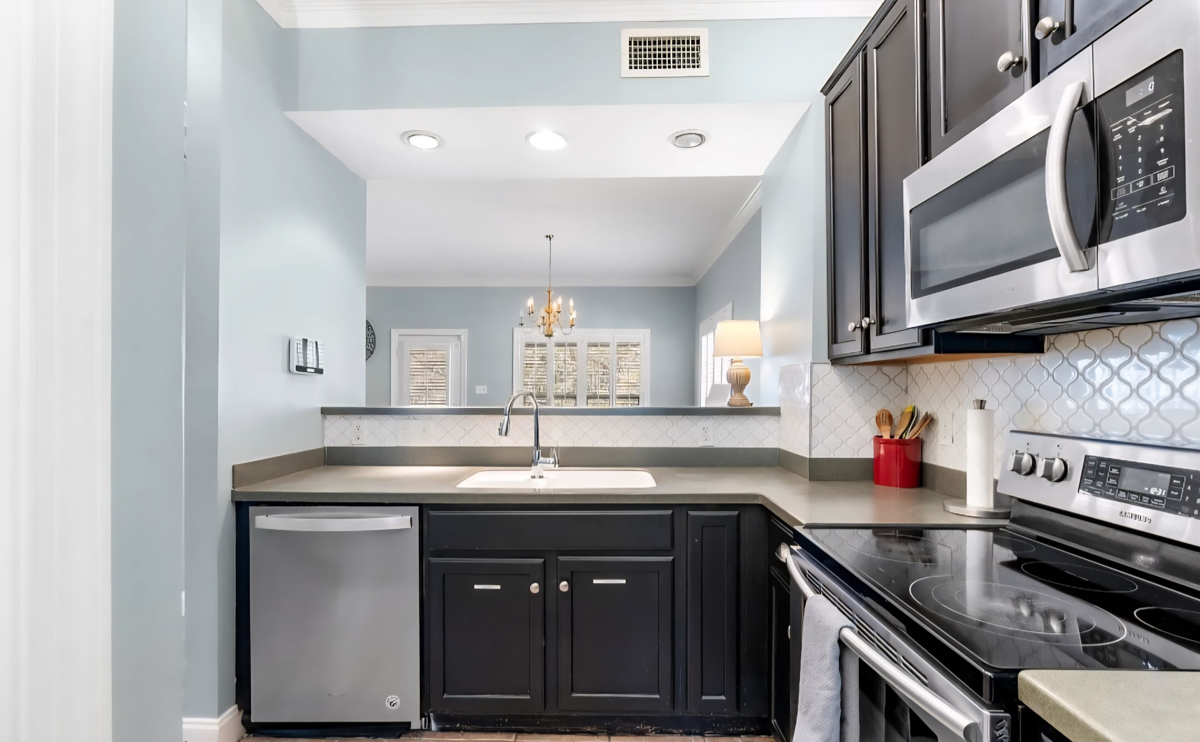 A modern kitchen with stainless steel appliances, a dishwasher, and black cabinetry.