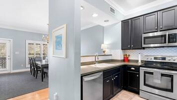 A modern kitchen with black cabinets, stainless steel appliances, and a dining area with a table and chairs.