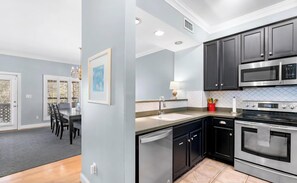 A modern kitchen with black cabinets, stainless steel appliances, and a dining area with a table and chairs.