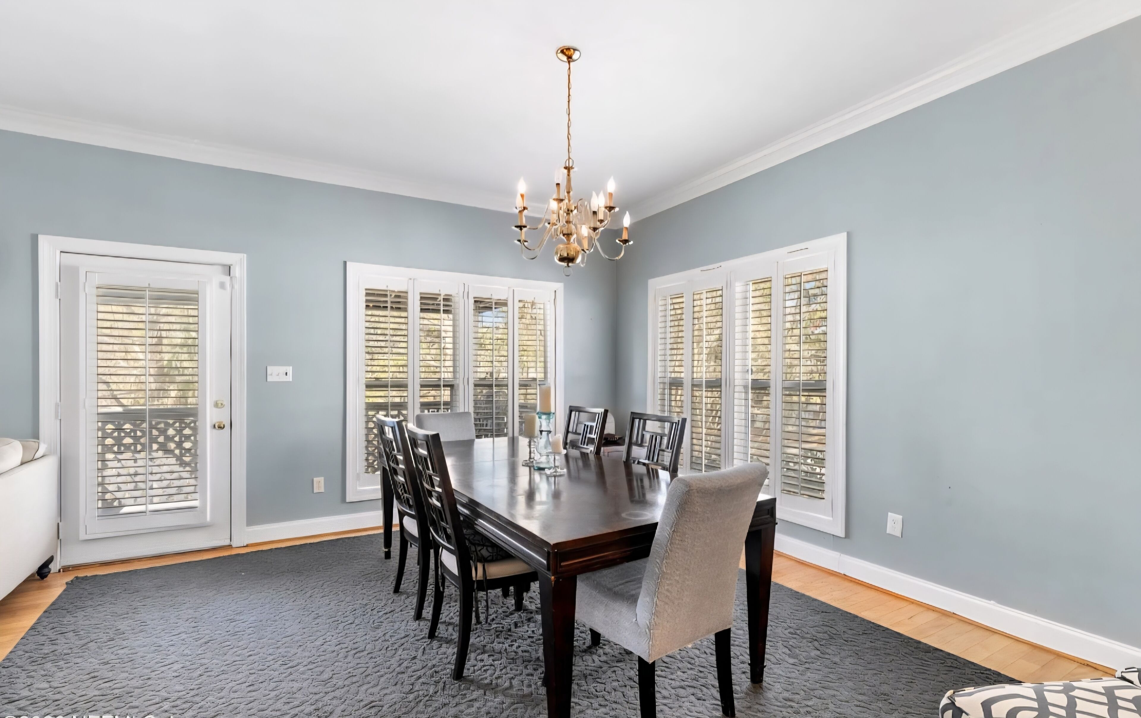 A dining room with a dark wooden table, six chairs, and a chandelier.