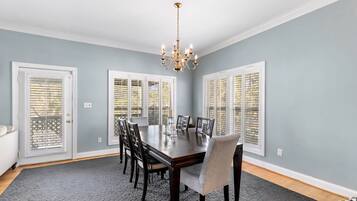 A dining room with a dark wooden table, six chairs, and a chandelier.