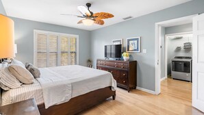 Ein Schlafzimmer mit Bett, Kommode, Fernseher und Deckenventilator.