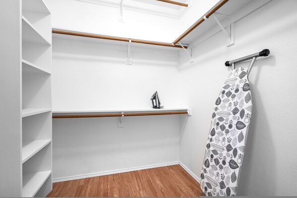 Ein begehbarer Kleiderschrank mit weißen Wänden, Holzboden und einer Decke mit Oberlichtern.