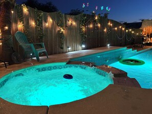 A backyard with a swimming pool, a hot tub, and a wooden fence adorned with string lights. - Candy’s Garden Vacation House - Spacious 5-bedroom Las Vegas (Las Vegas)