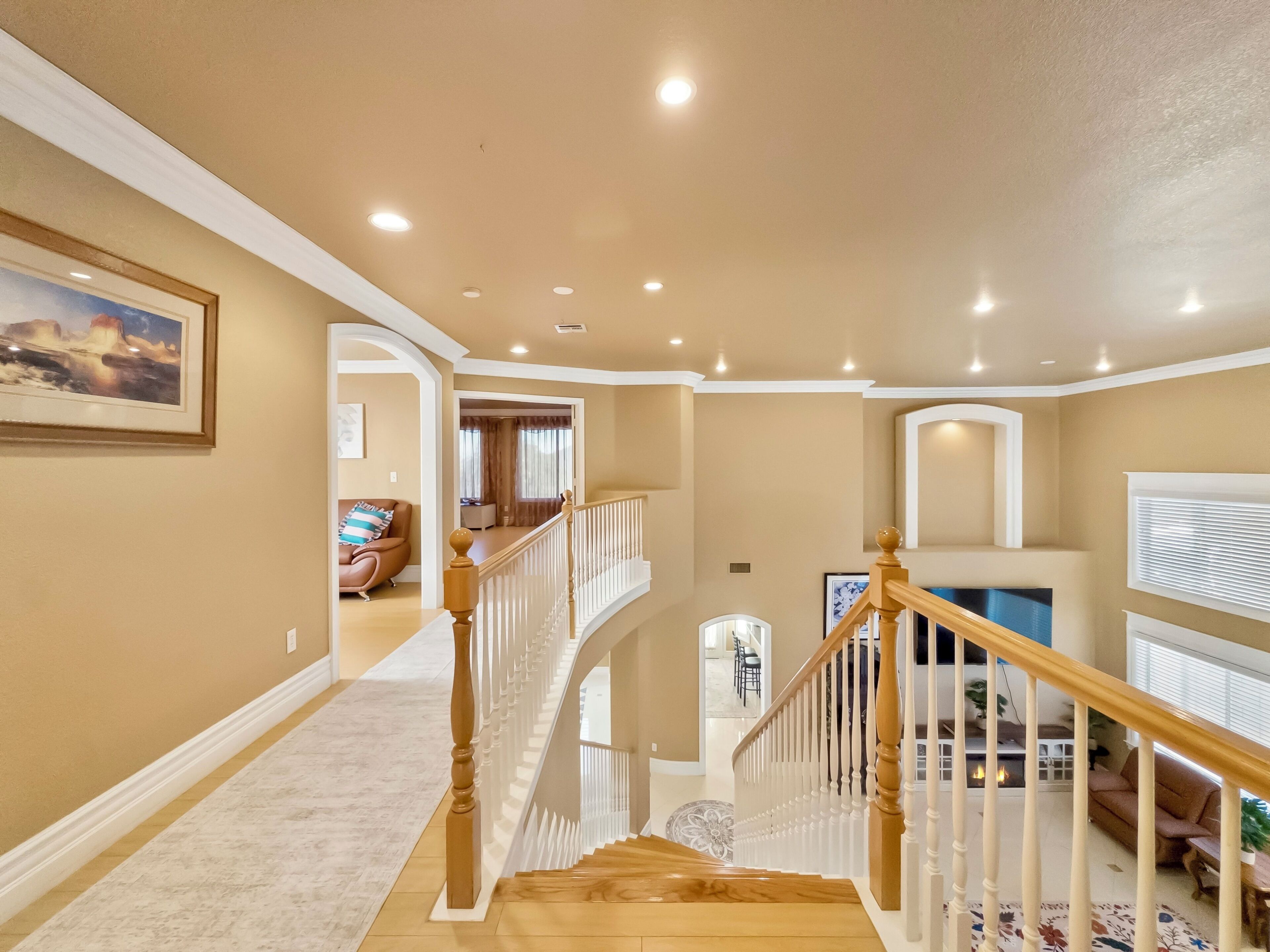 A spacious interior with a wooden staircase, a fireplace, and a living area with a sofa and a TV.