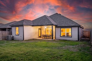 A residential house with a covered patio, a fenced yard, and a clear sky. - One Level Home Foosball Crib Office Space Yard (Crowley)