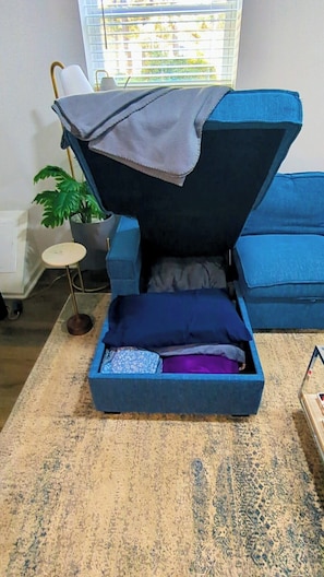 A room with a blue sofa, a small round table, and a potted plant. - Gorgeous Garden Level Retreat, Close to All! (Charlotte)
