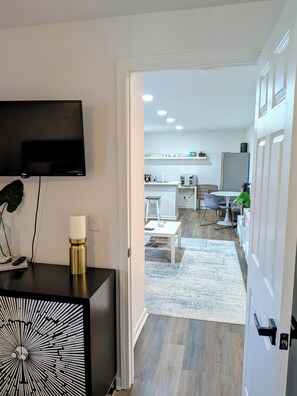 A modern living room with a flat-screen TV, a decorative candle, and a unique black and white wall art piece. - Gorgeous Garden Level Retreat, Close to All! (Charlotte)