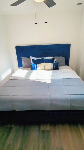 A bed with a blue headboard, white bedding, and a ceiling fan. - Gorgeous Garden Level Retreat, Close to All! (Charlotte)