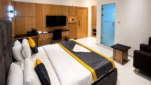 Una habitación de hotel moderna con una cama grande, un escritorio, un televisor y una puerta azul.