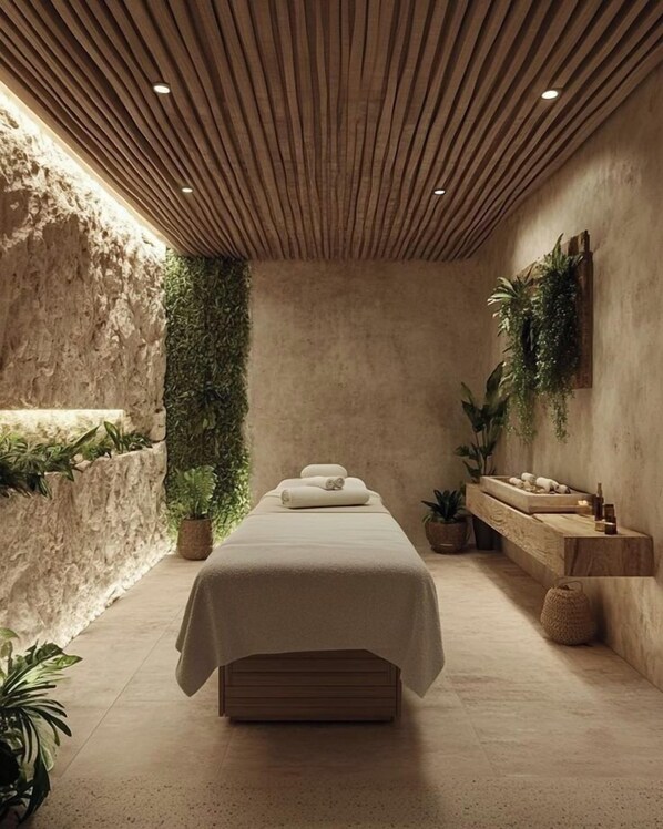 A spa room with a wooden ceiling, a bed, a wall-mounted shelf with plants, and a stone wall.