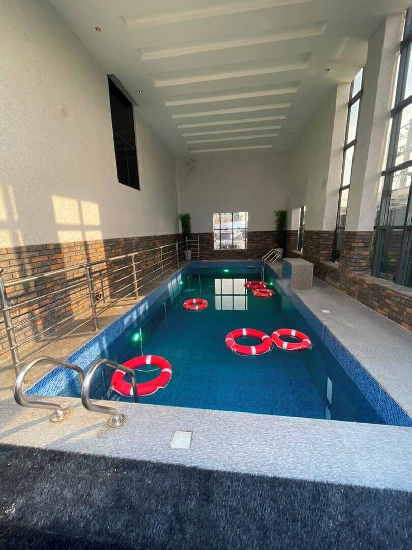 An indoor swimming pool with clear water, safety rings, and a tiled floor.