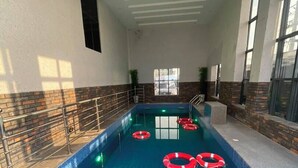 Una piscina interior con agua cristalina, anillos de seguridad y suelo de baldosas.