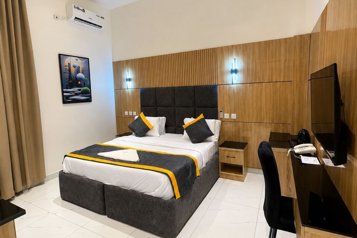 Una habitación de hotel moderna con una cama grande, un escritorio, una silla y un televisor.