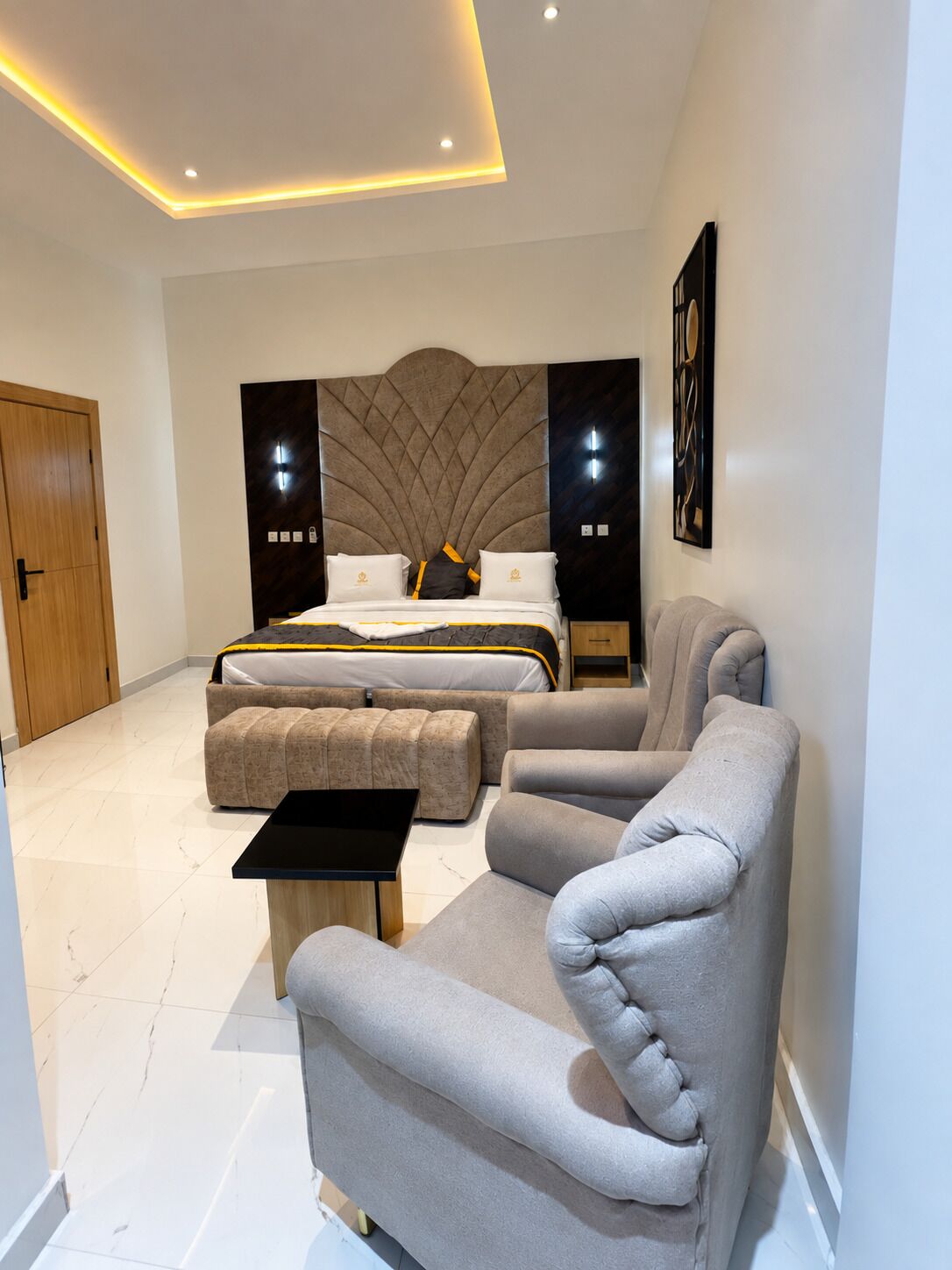 Une chambre moderne avec un lit, deux tables de chevet, un canapé et une petite table.