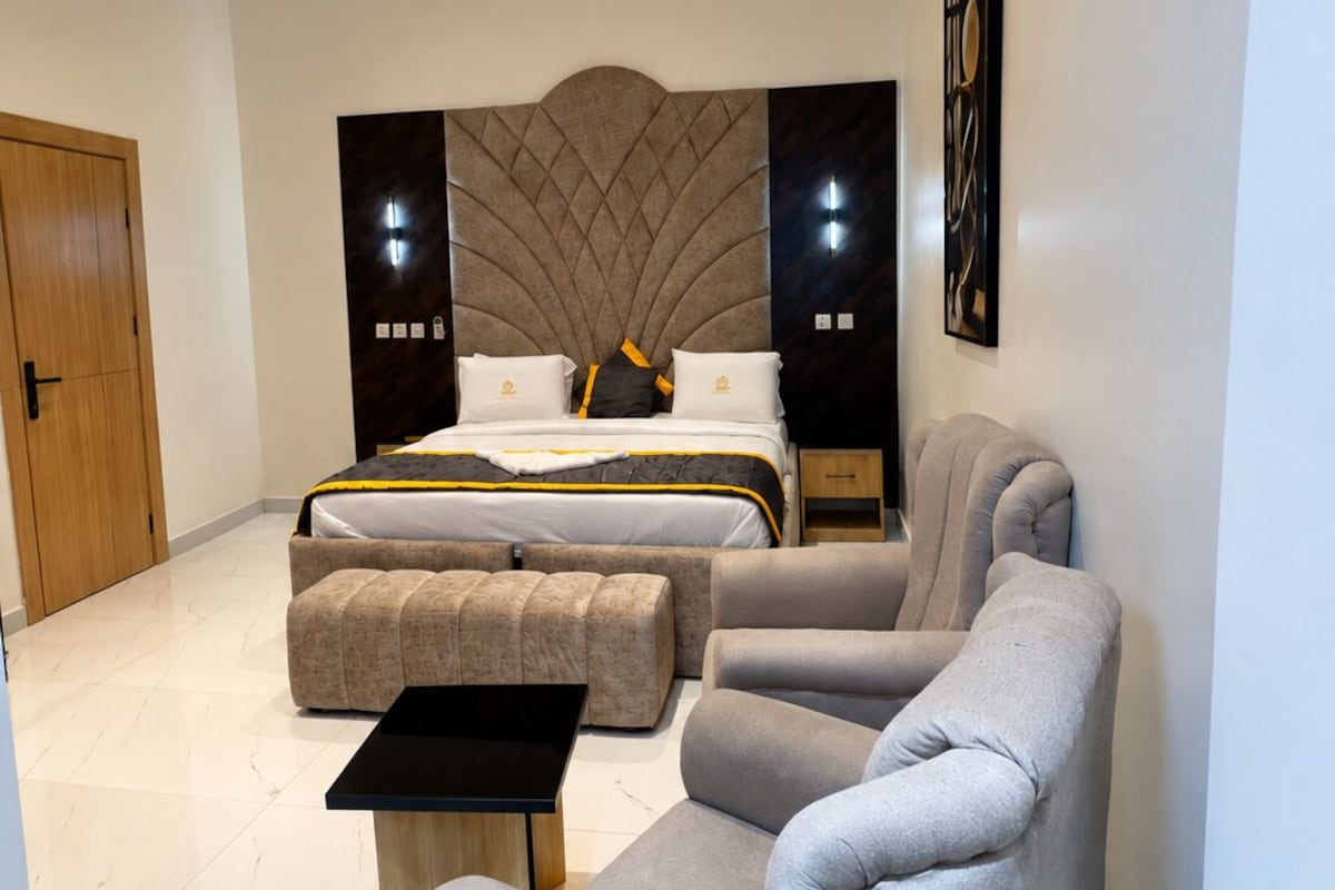 Un dormitorio moderno con cama, dos mesitas de noche, un sofá y una pequeña mesa.