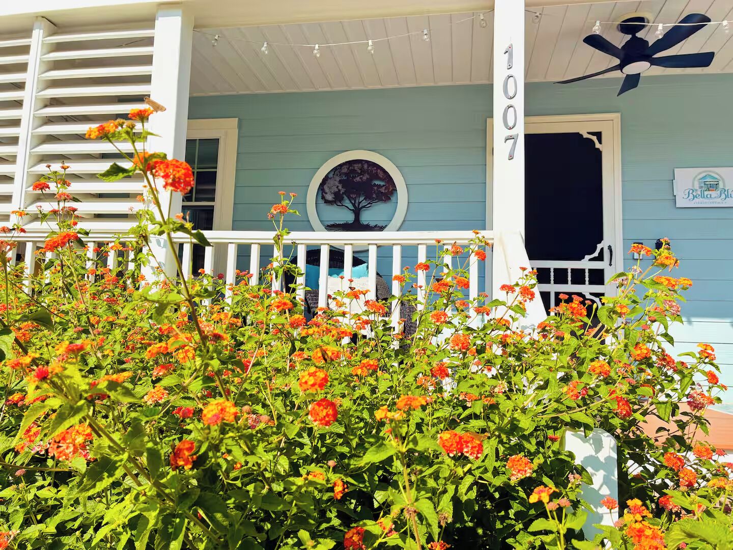 A porch with a white railing, a number sign, and a decorative tree mural.