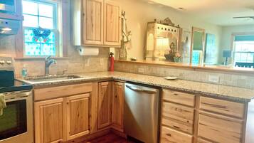 A kitchen with wooden cabinets, a stainless steel dishwasher, and a granite countertop.