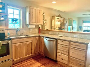 A kitchen with wooden cabinets, a stainless steel dishwasher, and a granite countertop. - Convenient Location in Town, Perfect for Two! (Beaufort)