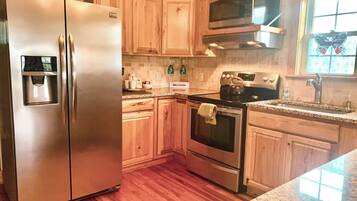 A kitchen with wooden cabinets, stainless steel appliances, a microwave, and a window with a butterfly decoration.