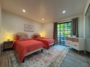 A bedroom with two beds, a nightstand, a dresser, and a window with curtains. - Pico-Robertson 2BR/2BA • King Bed • Free Parking • Near Rodeo Dr (Beverly Hills)