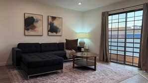 Ein modernes Wohnzimmer mit einem dunkelgrauen Sofa, einem runden Couchtisch und zwei abstrakten Bildern an der Wand.