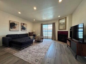 A modern living room with a sofa, a television, and a fireplace. - Pico-Robertson 2BR/2BA • King Bed • Free Parking • Near Rodeo Dr (Beverly Hills)