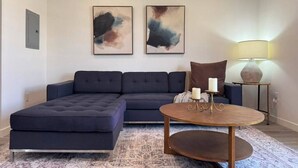 Ein modernes Wohnzimmer mit einem Ecksofa, einem runden Couchtisch und abstrakter Wandkunst.