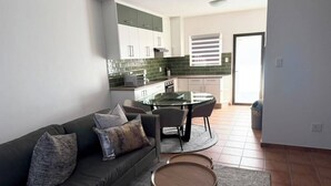 A modern living room with a sofa, coffee table, and dining area. - Superb 2-bedroom apartment in adorable Windhoek neighborhood (Windhoek)