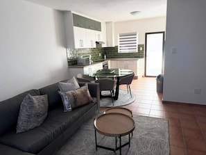 Ein modernes Wohnzimmer mit Sofa, Couchtisch und Essbereich.