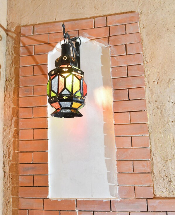 A lantern with a geometric pattern, hanging from a brick wall. - Ferme Dar Charach (Tarmigt)