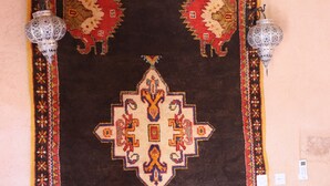 A room with a bed, a wall tapestry, and two wall-mounted lamps. - Ferme Dar Charach (Tarmigt)