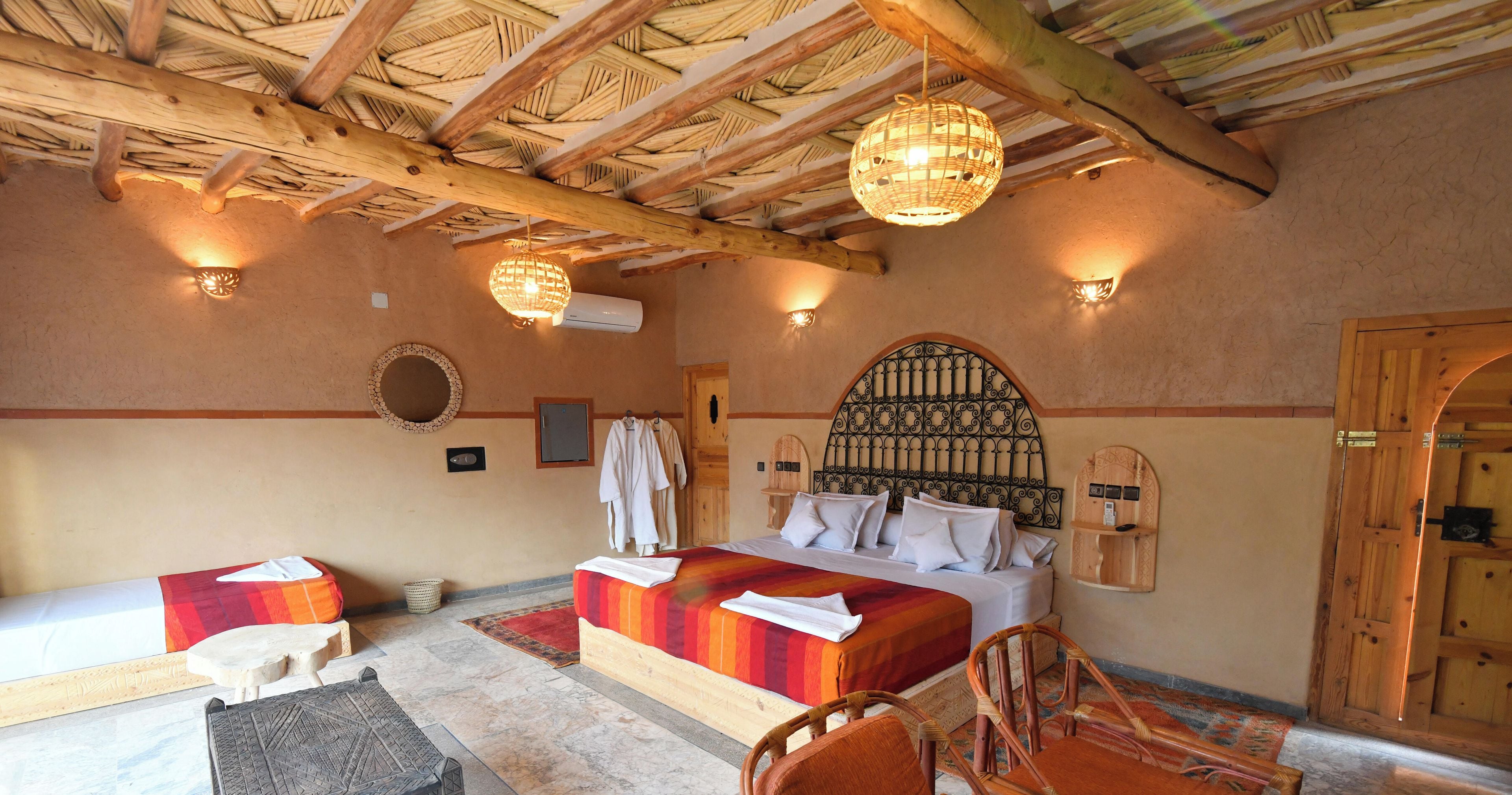 Una habitación de hotel con cama, dos sillas, una mesita, un espejo y un calentador de pared.