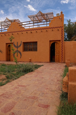 Un edificio con un patio, una puerta de madera y una ventana con diseño de cuadrícula.