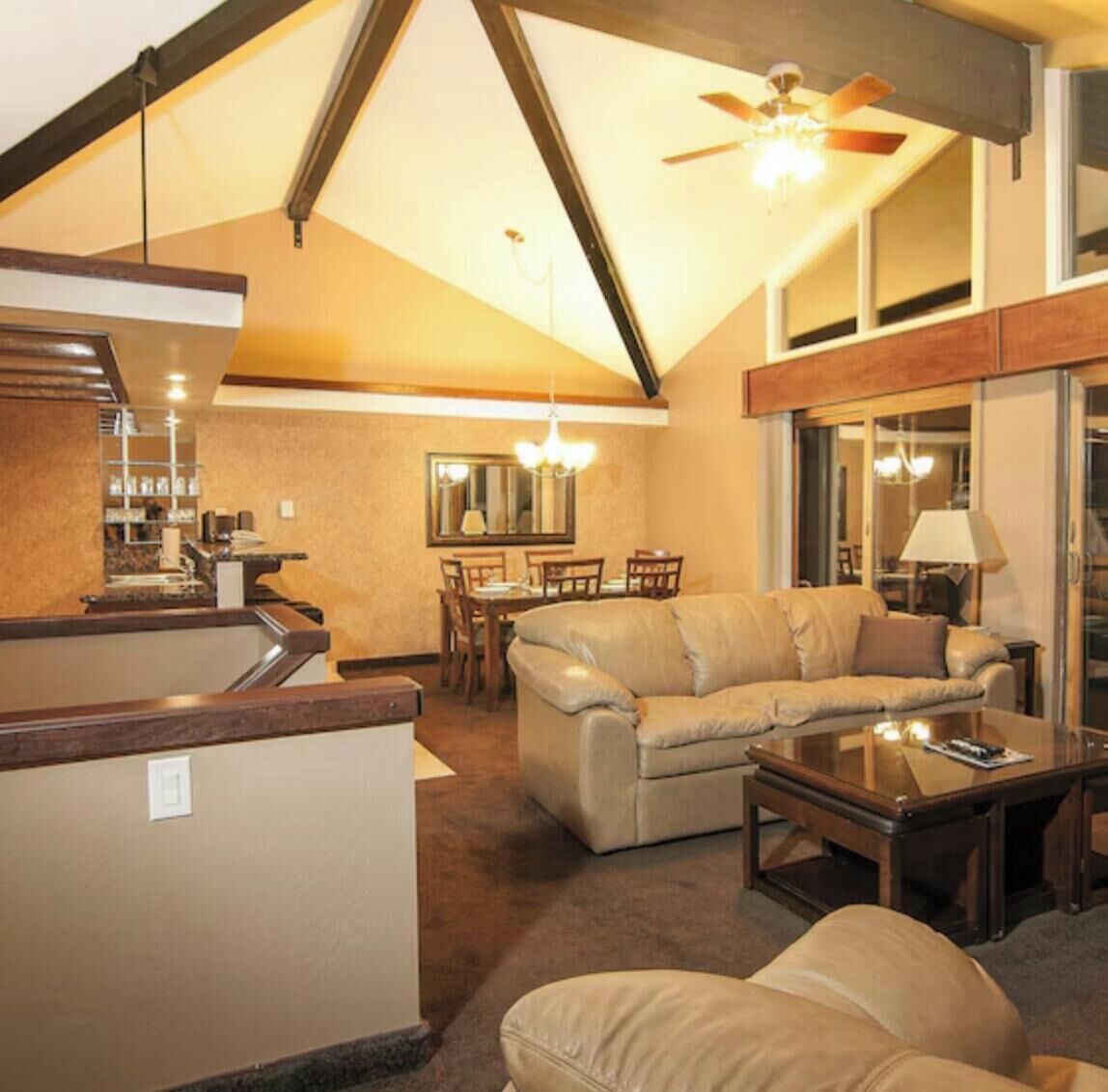 A living room with a sofa, a coffee table, and a dining area with chairs and a table.