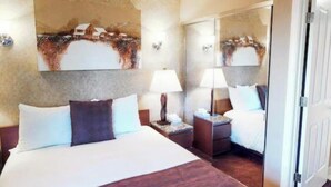 A hotel room with a large bed, two bedside tables with lamps, a mirror, and a painting on the wall. - Beautiful 2-bedroom condo in quaint Incline Village perfect for relaxing (Incline Village)